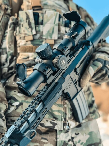 Оптичен прицел Vortex Optics детайлно върху модерна щурмова пушка с монтаж върху Picatinny релса, стрелец в камуфлажи. Снимка: Rigad