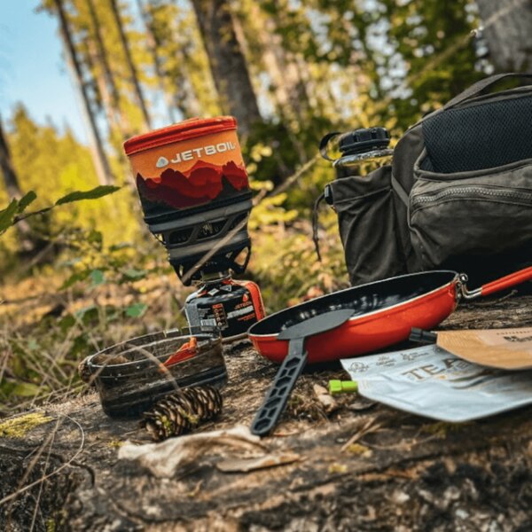 Открит газов котлон Jetboil с тиган и аксесоари в гората. Снимка: Rigad