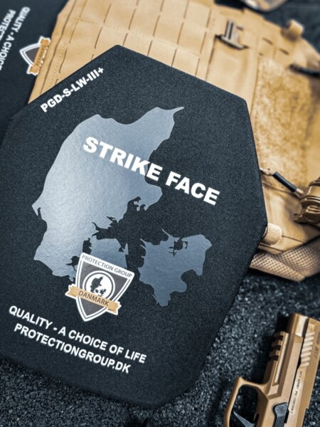 Твърда балистична плоча със STRIKE FACE страна (PGD); на заден план носач на плочи и служебен пистолет, детайл преди поставяне в носача.