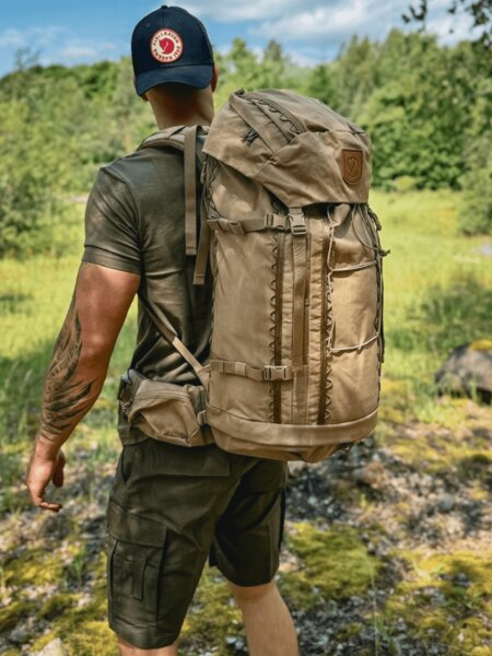Мъж с раница и шапка на Fjällräven на лятна разходка като превантивна мярка против слънчев удар. Снимка: Rigad