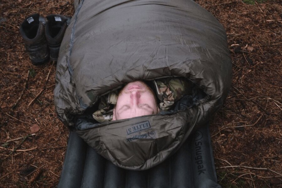 Мъж в камуфлаж лежи на надуваем дюшек в спален чувал Softie<sup>®</sup> Elite 5 Snugpak<sup>®</sup>. Източник: Rigad, Snugpak