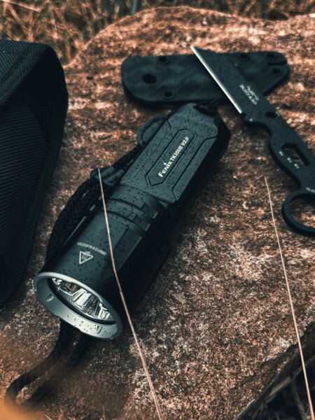 Тактическо фенерче TK35 Ultimate Edition Fenix<sup>®</sup> на мокър камък в outdoor среда. Снимка: Rigad