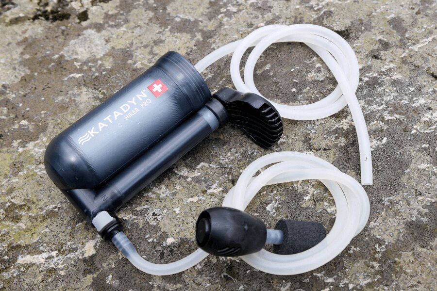 Помпена воден филтър Katadyn Hiker Pro с маркучи, поставен върху камък. Снимка: Rigad