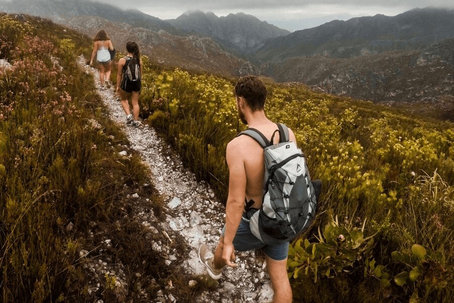 Мъж без тениска и две жени на планински път. Източник: https://www.pexels.com/cs-cz/foto/930685/