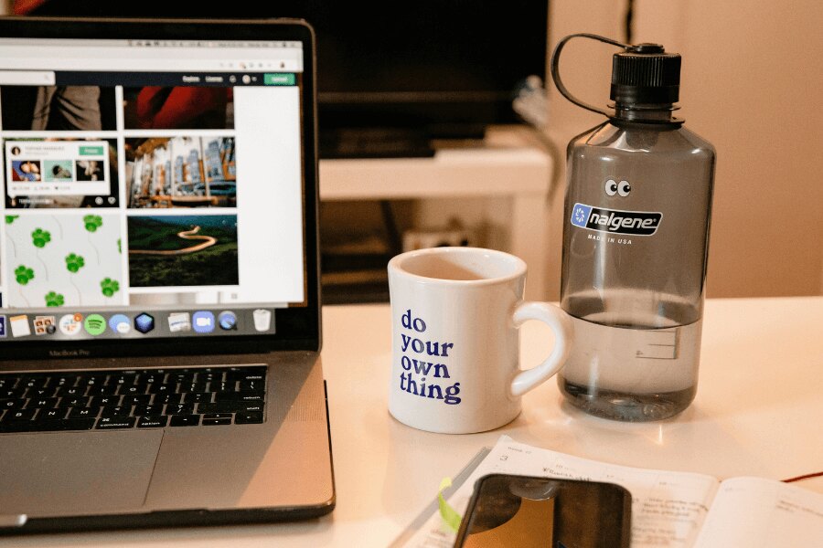 Бутилка Nalgene на работната маса до macbook. Източник: https://www.pexels.com/cs-cz/foto/kava-salek-notebook-internet-3959986/