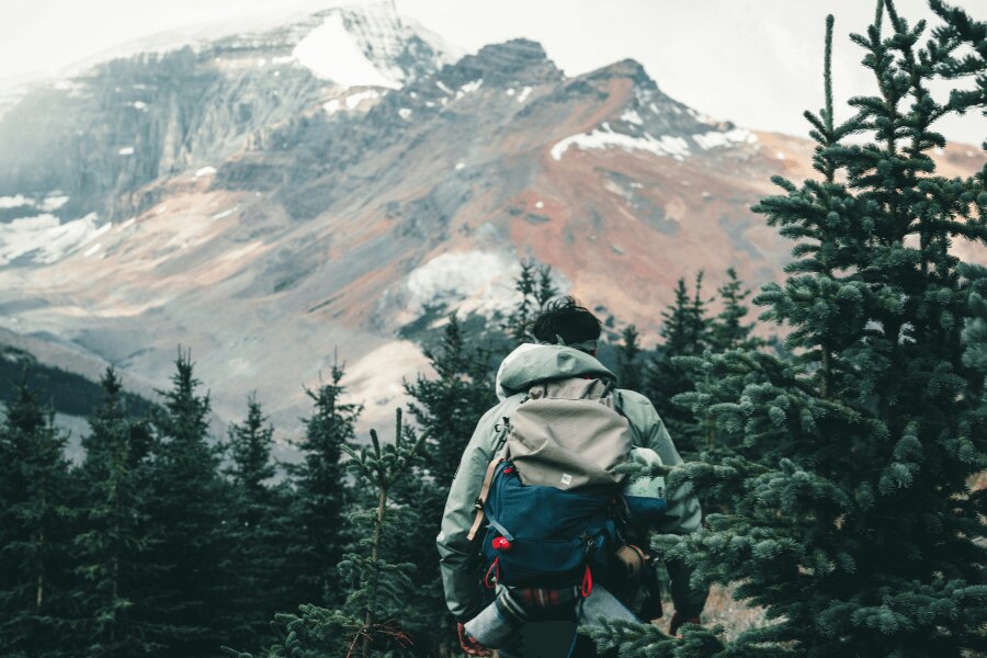 Мъж в планините с функционално яке. Източник: https://www.pexels.com/cs-cz/foto/snih-osoba-hora-tramp-10772381/