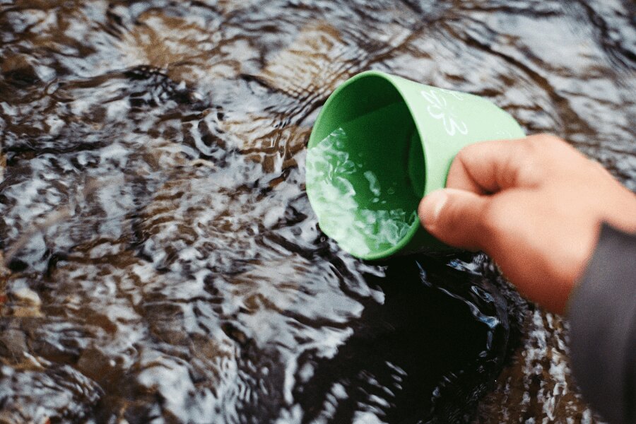 Набиране на вода в потока в зелена чашка. Източник: https://www.pexels.com/cs-cz/foto/66090/