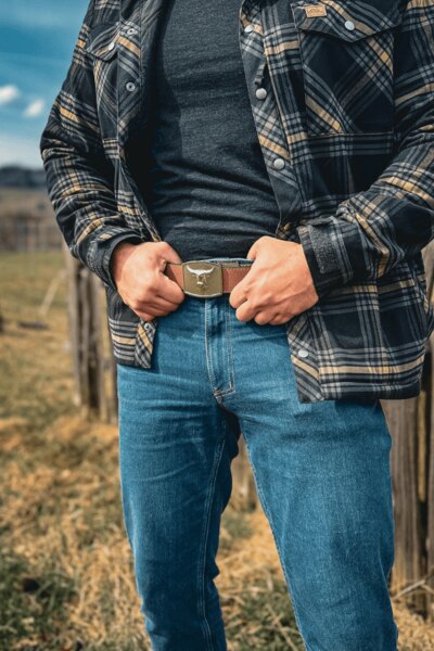 Мъж в панталони Treadstone Jeans<sup>®</sup> Helikon-Tex<sup>®</sup> с карирана риза се държи за колана. Снимка: Rigad