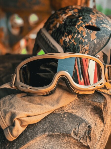 Тактически защитни очила тип goggles, поставени върху оборудването, в задния план каска; пример за използване в труден терен. Снимка: Ригад