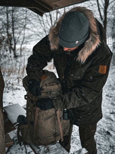 Здрав солиден експедиционен раница Fjällräven Kajka, поставена в снега, готова за зимно многодневно пътешествие. Фото: Rigad