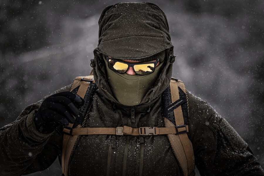 Турист в зимна виелица с издръжливо изолирано яке Helikon-Tex Yukon с балаклава и защитни очила при труден зимен изкачване. Снимка: Rigad