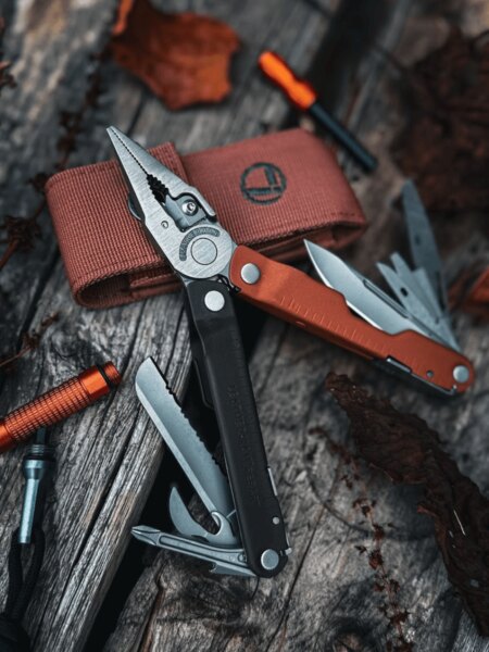 Многофункционален инструмент Leatherman Rebar с разгънати клещи и извадени инструменти върху дървена повърхност.