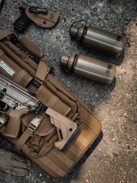 Две полеви бутилки TacValve<sup>®</sup> ModCan поставени до стрелковото оборудване и самозареждащата се пушка.