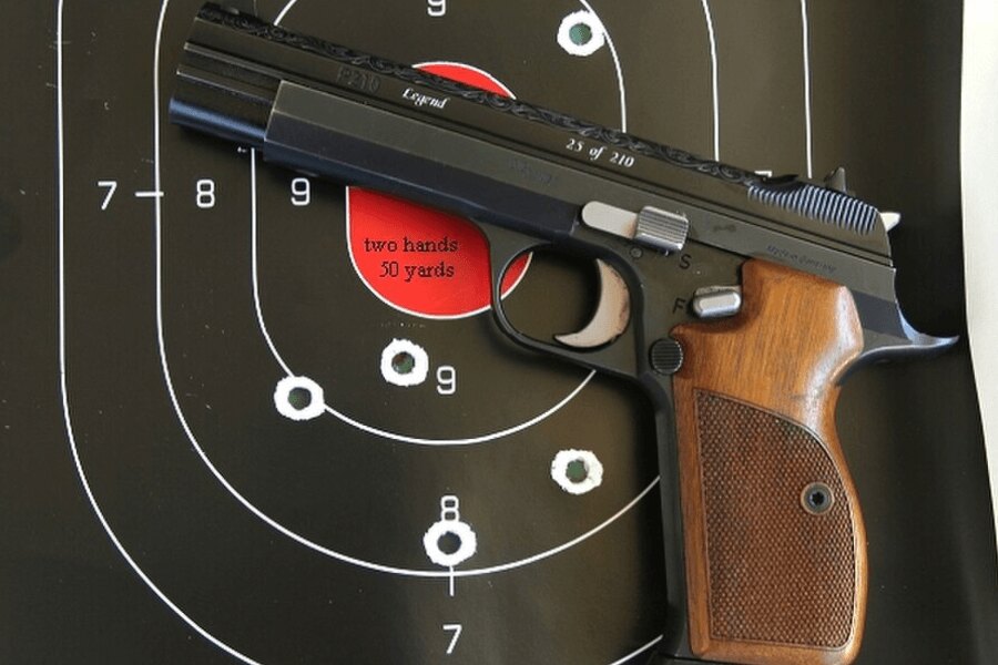 Пистолет "SIG P210", поставен пред стрелкова мишена.