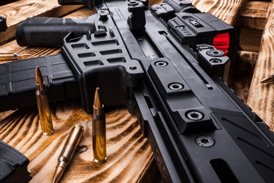 Детайл на самозарядна пушка "CZ BREN 2" с колиматор върху дървена маса.