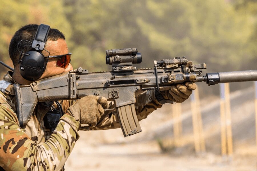 Стрелец с пушка "FN SCAR", оборудвана с колиматор, фенер и заглушител.