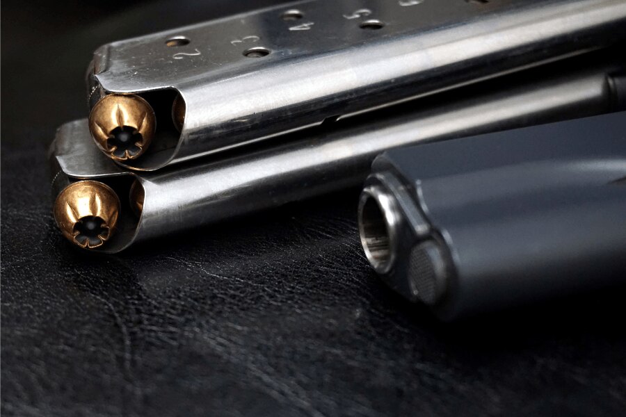Детайл на пълнителя на пистолет "M1911" с патрони .45 ACP и на заден план част от пистолетаплан.
